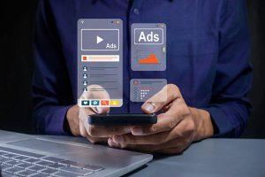 数字营销人员在手机上管理谷歌展示广告（GDN）活动，屏幕显示视频广告与数据分析图表。